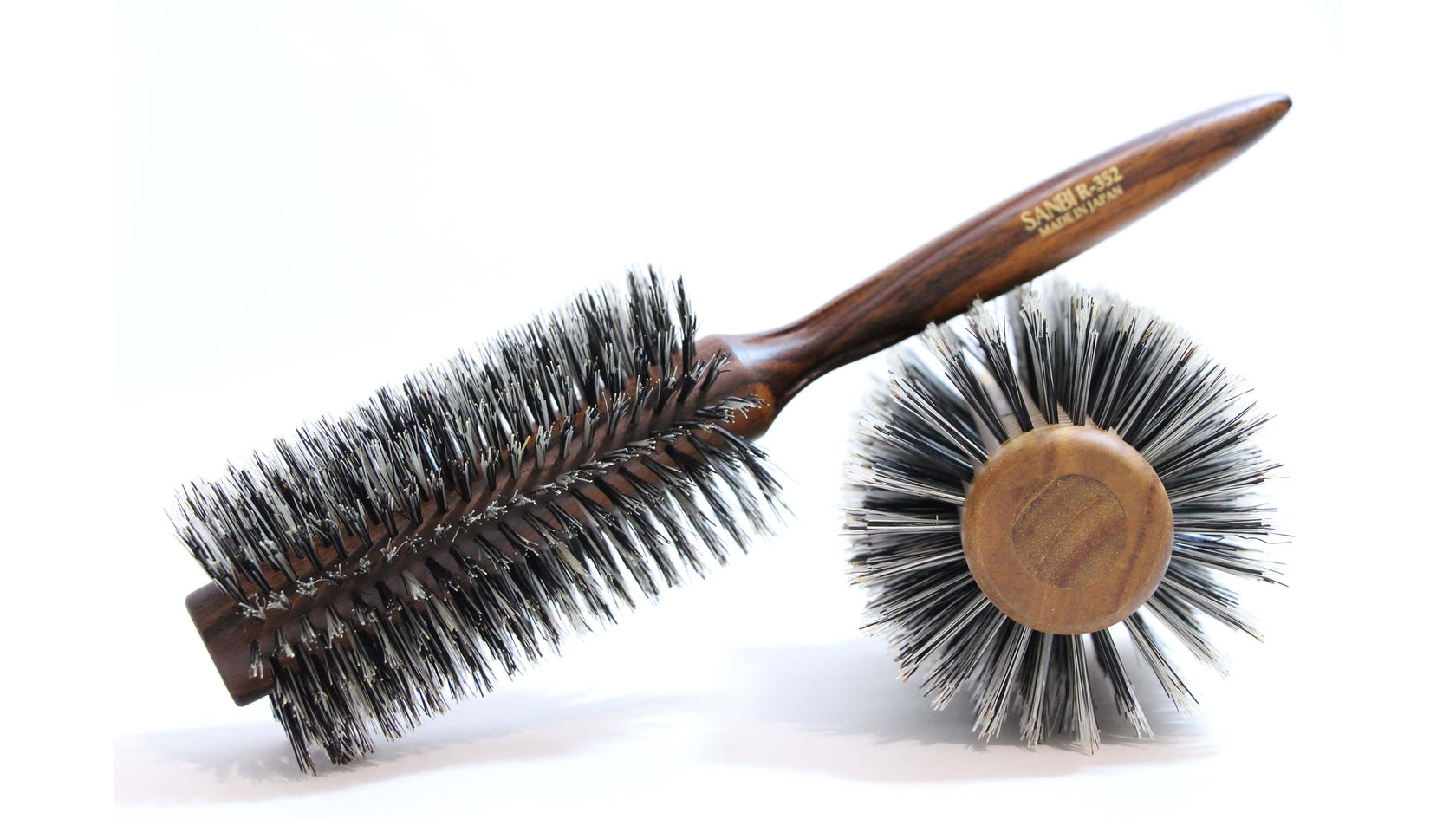 brosses rondes de la marque sanbi en poil de sanglier, l'une est à l'envers et à l'autre en diagonal